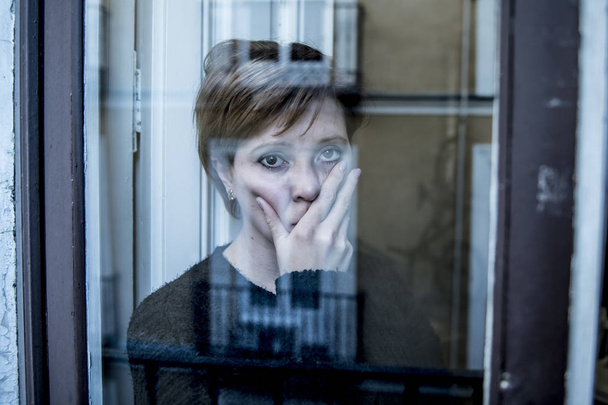 dramatic close up portrait of young beautiful woman thinking and  feeling sad suffering depression at home window looking depressed - Fotografie, Obrázek
