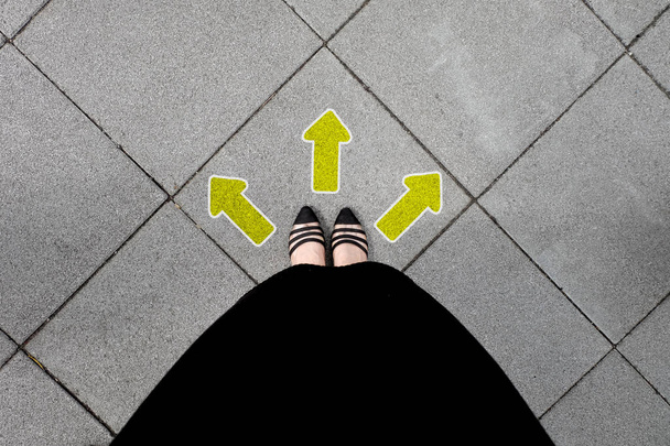 Flecha direccional y par de zapatos negros mujer de pie sobre el fondo del azulejo ideal para cualquier uso
. - Foto, Imagen