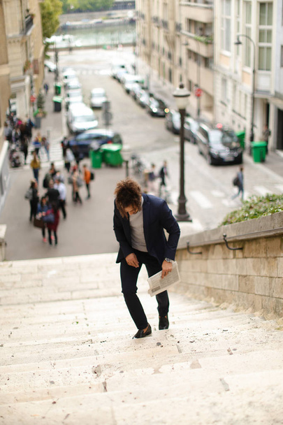 Mulato chico caminando por los escalones con periódico
. - Foto, Imagen