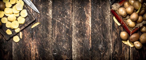 The sliced potatoes on an old wooden Board. On wooden background. - Фото, изображение