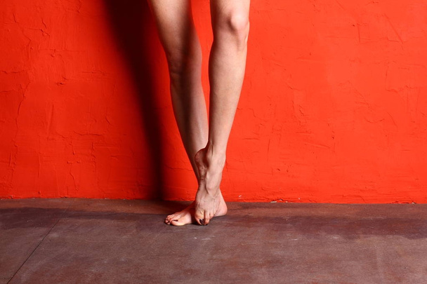 Naked woman ballerinas legs on red wall background. - Foto, imagen