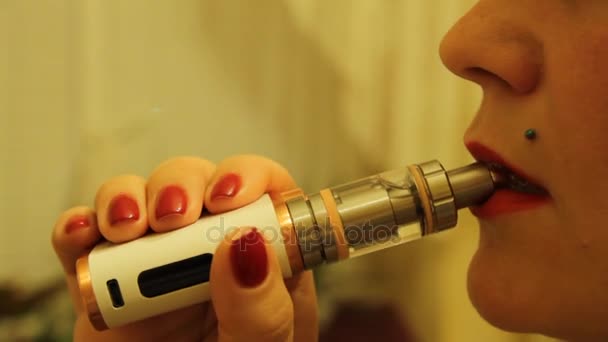 A menina fuma um vaporizador eletrônico de cigarro e libera vapor de fumaça de sua boca
. - Filmagem, Vídeo