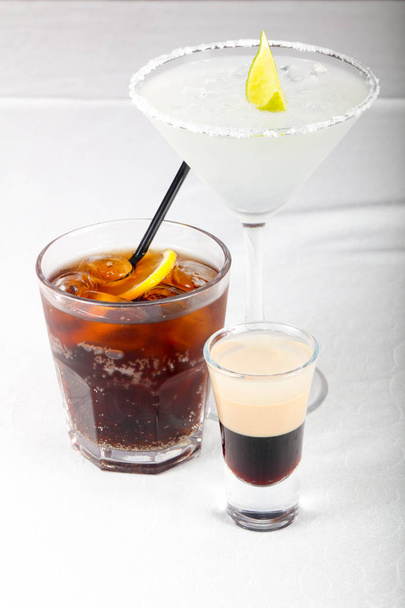 Ассортимент алкогольных коктейлей на белом столе
 - Фото, изображение