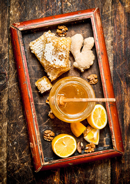 Fondo de miel. Miel fresca con limón y jengibre en una bandeja vieja
. - Foto, imagen