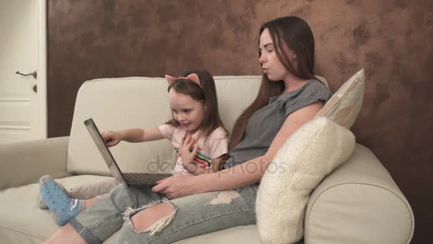 Little girl shows something to her mother on the laptop - Filmati, video