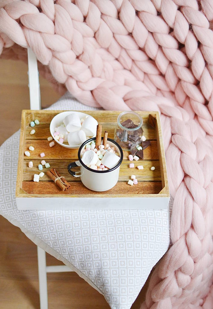 Κούπα με ζεστή σοκολάτα, μπολ με marshmallows, βάζο με σοκολάτα, ροζ παστέλ καρό γίγαντας, λευκή καρέκλα, πρωί έννοια - Φωτογραφία, εικόνα