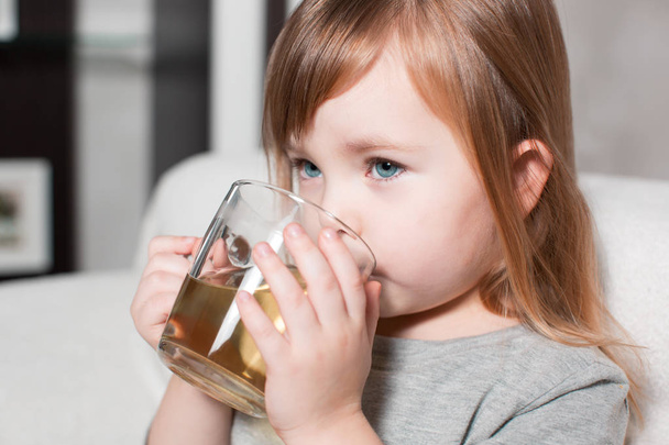 Little girl holding a cup of tea - Фото, изображение