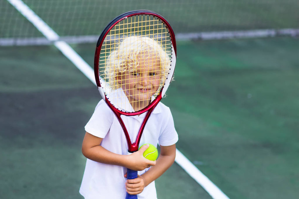 Дитина грає в теніс на відкритому корті
 - Фото, зображення
