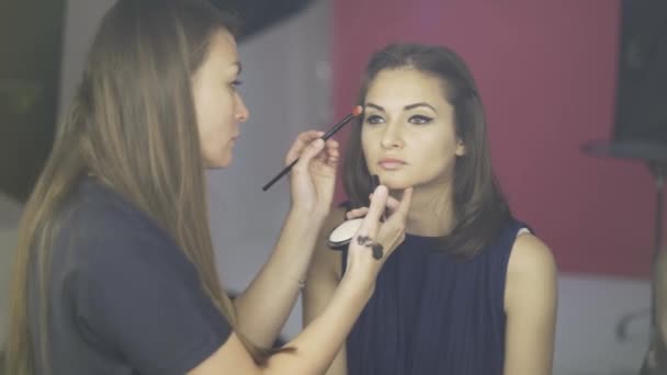 Make up artist applying a toning cream to a model s face in a studio - Felvétel, videó