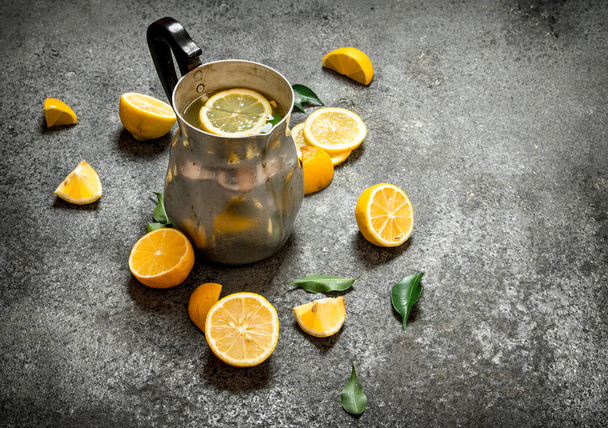 Cold lemonade in a jug with slices of lemon and green leaves. - 写真・画像