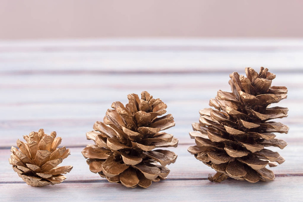 Fermer cônes de pin doré sur un fond de table en bois blanc
. - Photo, image