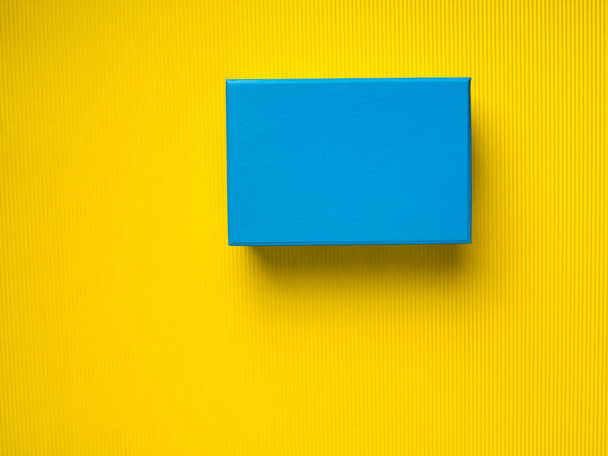 Caixa de presente azul no fundo amarelo
 - Foto, Imagem