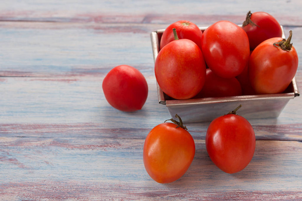 крупним планом червоні вишневі помідори в нержавіючій мисці на дерев'яній тарілці
 - Фото, зображення
