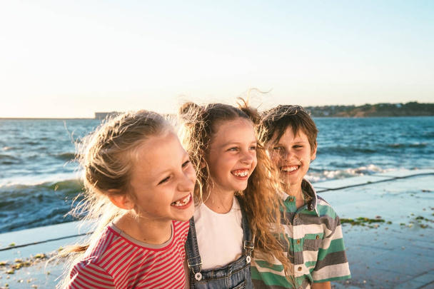 Close up portrait of three happy teenage kids walk along the waterfront and laughing - Foto, imagen