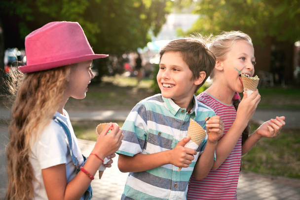 Close-up portrait of three happy preteen children walking on the street, having fun and eating ice-cream - Foto, Imagem