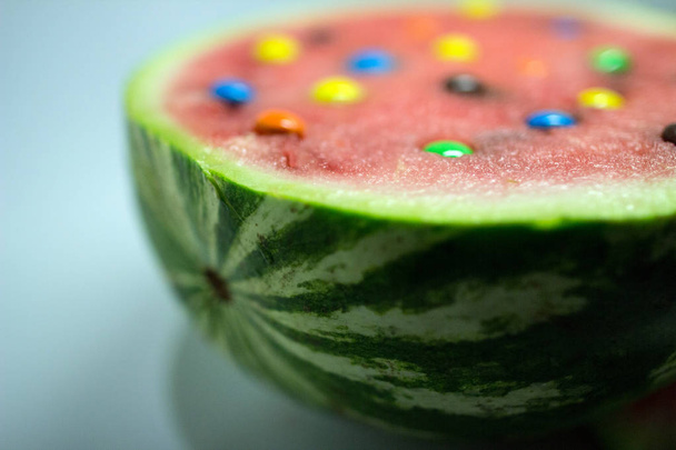 half of red watermelon with colored candy. isolated fruit. - Foto, Bild