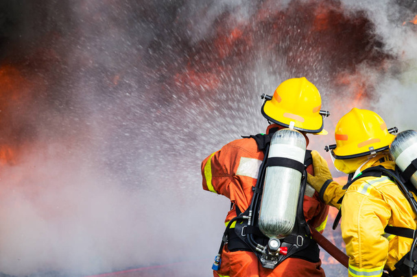 two firefighters water spray by high pressure nozzle to fire sur - Photo, Image