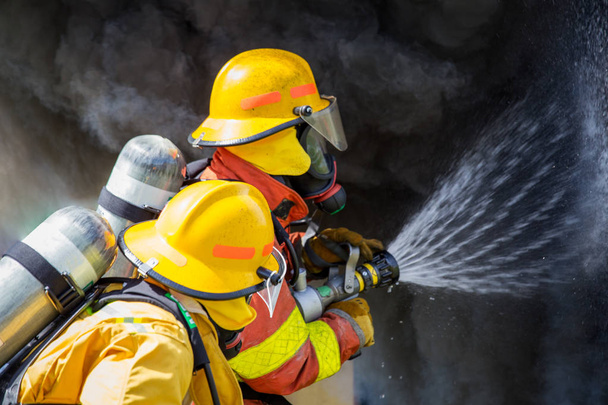 two firefighters water spray by high pressure nozzle to fire sur - Фото, изображение