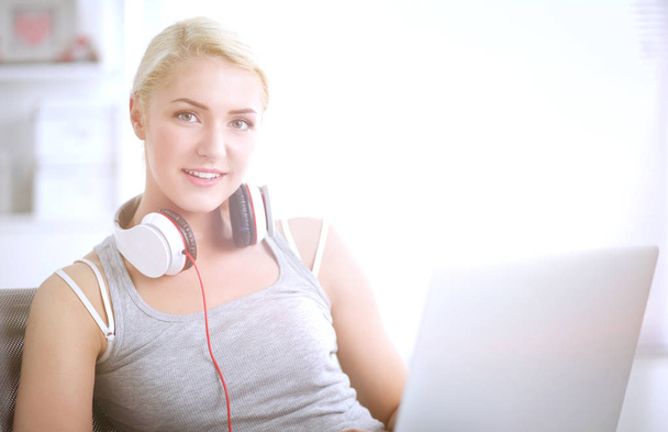 Young beautiful woman at home sitting on sofa and listening music - Foto, afbeelding