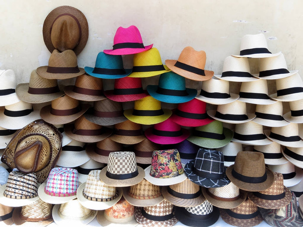 A stack of straw colored  hats of different colors on the street in Cartagena old town - Photo, Image