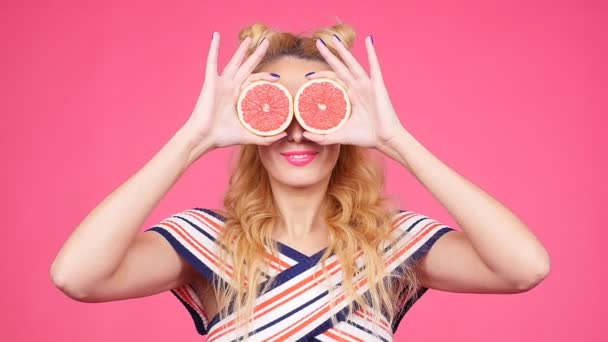 Gelukkig jonge vrouw met twee ogen helft van sappige grapefruit in plaats daarvan - Video