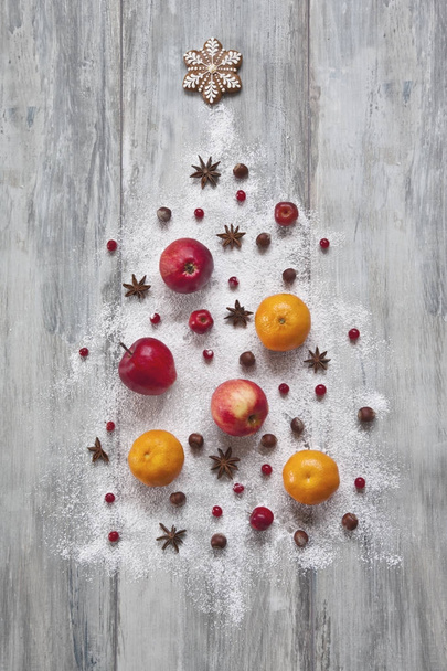 close-up of Mixed fruits and nuts with spices and Christmas decor in shape of fir tree on wooden background. Christmas concept. - Foto, Bild