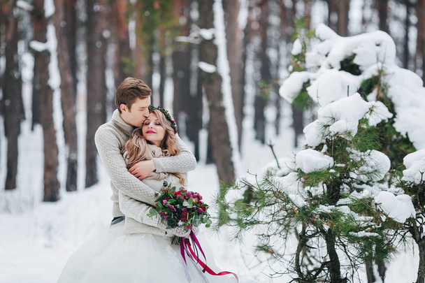 Groom is kissing bride on the temple in the snowy forest. Artwork. - Foto, afbeelding