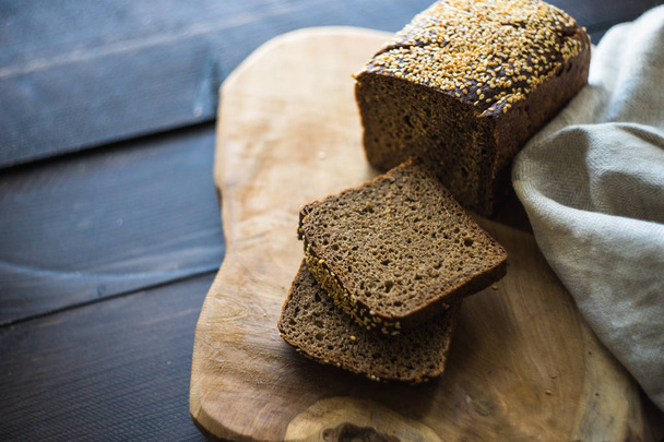 Chutný žitný chleba na prkénku na rustikální dřevěný stůl - Fotografie, Obrázek