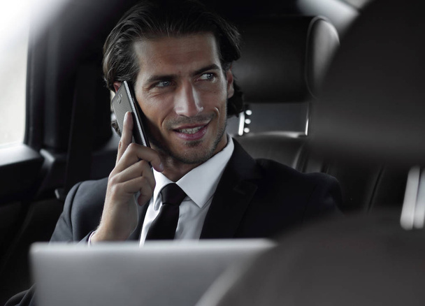 Handsome businessman using mobile phone in car. - Fotó, kép