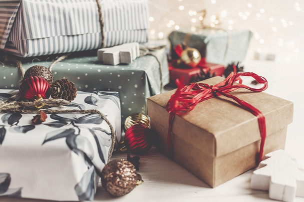 κοντινό πλάνο καλαίσθητα δώρα Χριστουγέννων τυλιγμένο με στολίδια και τα φώτα σε άσπρο φόντο ξύλινη - Φωτογραφία, εικόνα