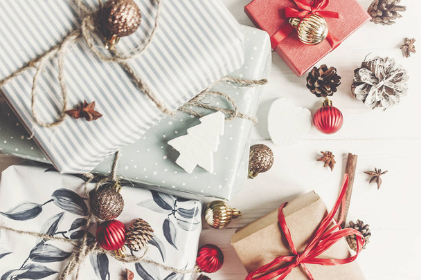Weihnachten flache Lage mit rustikalen farbigen Geschenkboxen mit Dekorationen auf weißem Holzhintergrund, Ansicht von oben - Foto, Bild