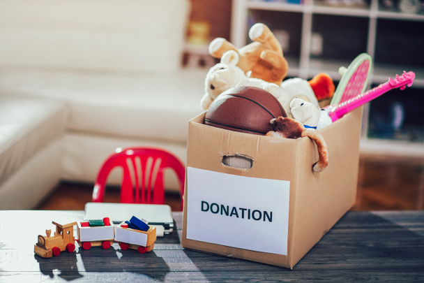 Spendenbox voll mit Sachen zum Spenden auf Holztisch - Foto, Bild