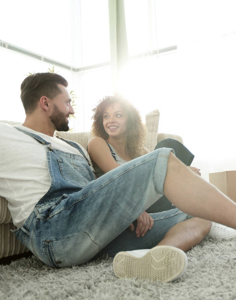 Happy married couple sitting on the carpet in a new apartment. - Foto, imagen