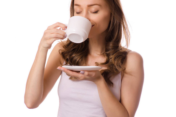 Beautiful young woman holding a white cup and saucer with coffee tea - Foto, Imagen