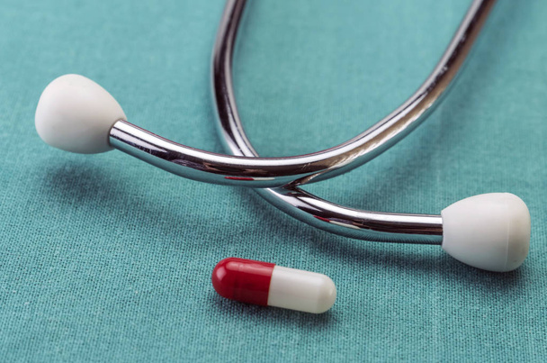 Rote und weiße Kapsel neben einem Stethoskop, Konzeptbild - Foto, Bild