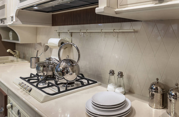 Luxuosa cozinha branco-leite em estilo clássico. Fogão a gás e pratos de metal brilhante
. - Foto, Imagem
