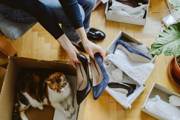 Жінка розв'язує нове взуття з милою домашньою кішкою, допомагаючи їй
 - Фото, зображення