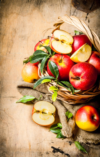Red apples in an old basket with leaves. - Φωτογραφία, εικόνα