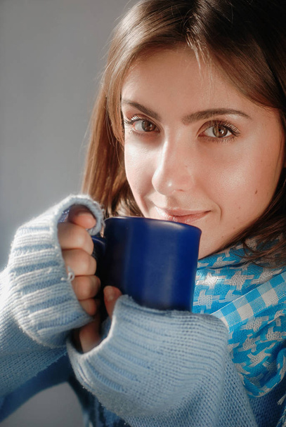 smiling dreaming girl in sweater with the cup near the frozen window in the winter - Fotografie, Obrázek