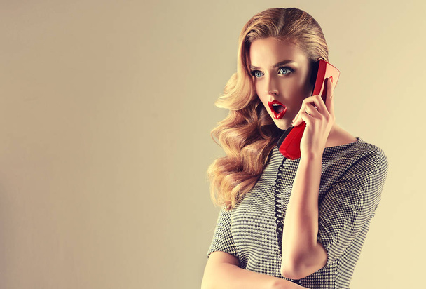 Beautiful woman in pin up style with vintage red phone.  Shocked pretty girl  . Presenting your product. Expressive facial expressions - Fotó, kép