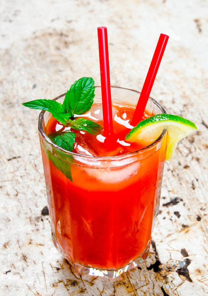 Cocktail made of tomatoes, vodka, ice, lime, pepper , salt on rustic background .  - Photo, Image