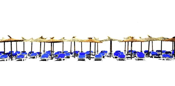 Chaise lounge de playa con sombrillas de paja aisladas
 - Foto, imagen