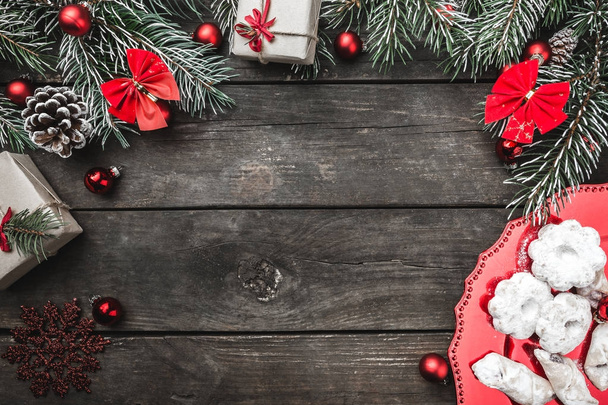 Tarjeta de felicitación navideña sobre fondo de madera, ramas de abeto, conos, espacio para mensajes, juguetes, dulces y regalos de Navidad. Vista superior
. - Foto, imagen