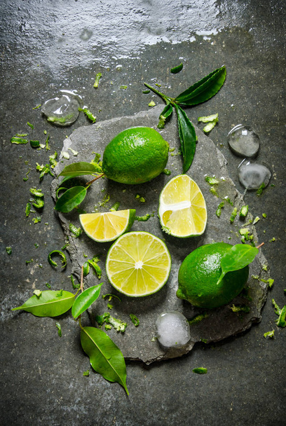 Lime background. Slices of lime with ice and leaves on a stone stand .  - Foto, Imagen