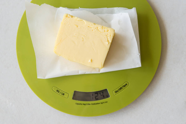 Fatia de manteiga na balança de cozinha digital
 - Foto, Imagem