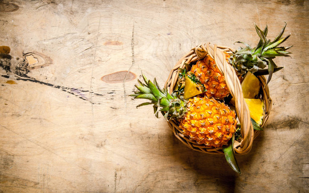 Fresh pineapples in the basket. On wooden table. - 写真・画像