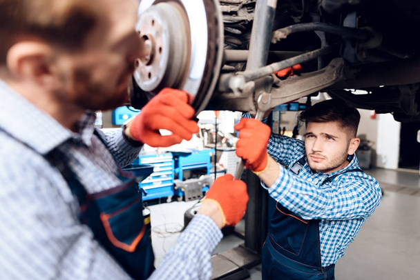 Father and son work at the auto service. Two mechanics work with the details of the car. - Foto, immagini