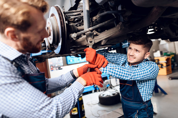 Father and son work at the auto service. Two mechanics work with the details of the car. - Foto, Imagem