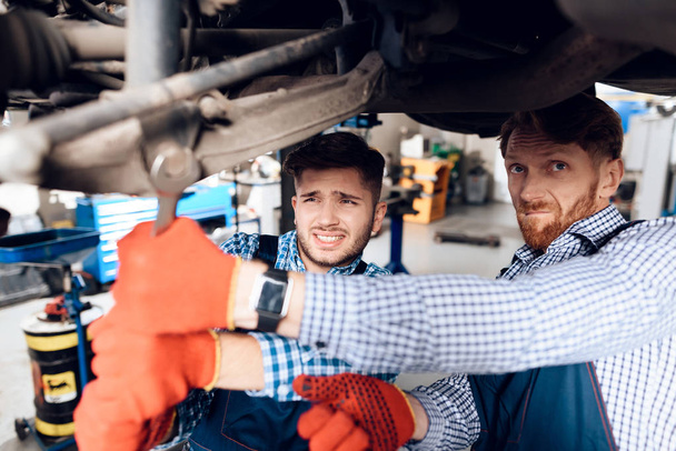 Father and son work at the auto service. Two mechanics work with the details of the car. - Foto, Imagem