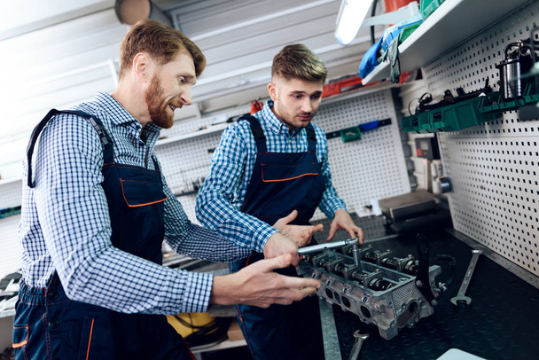 Father and son work at the auto service. Two mechanics work with the details of the car. - 写真・画像